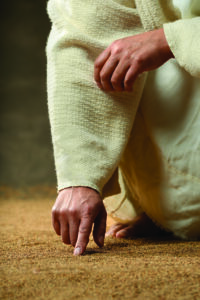 Jesus finger writing in the sand in close up view