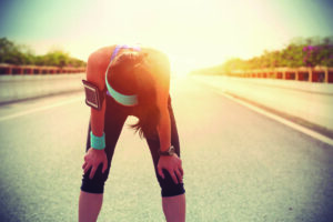 tired woman runner taking a rest after running hard on city road