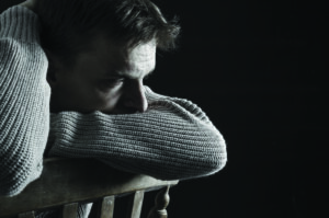 Sad depressed man sitting in the dark. Feelings of grief or loss