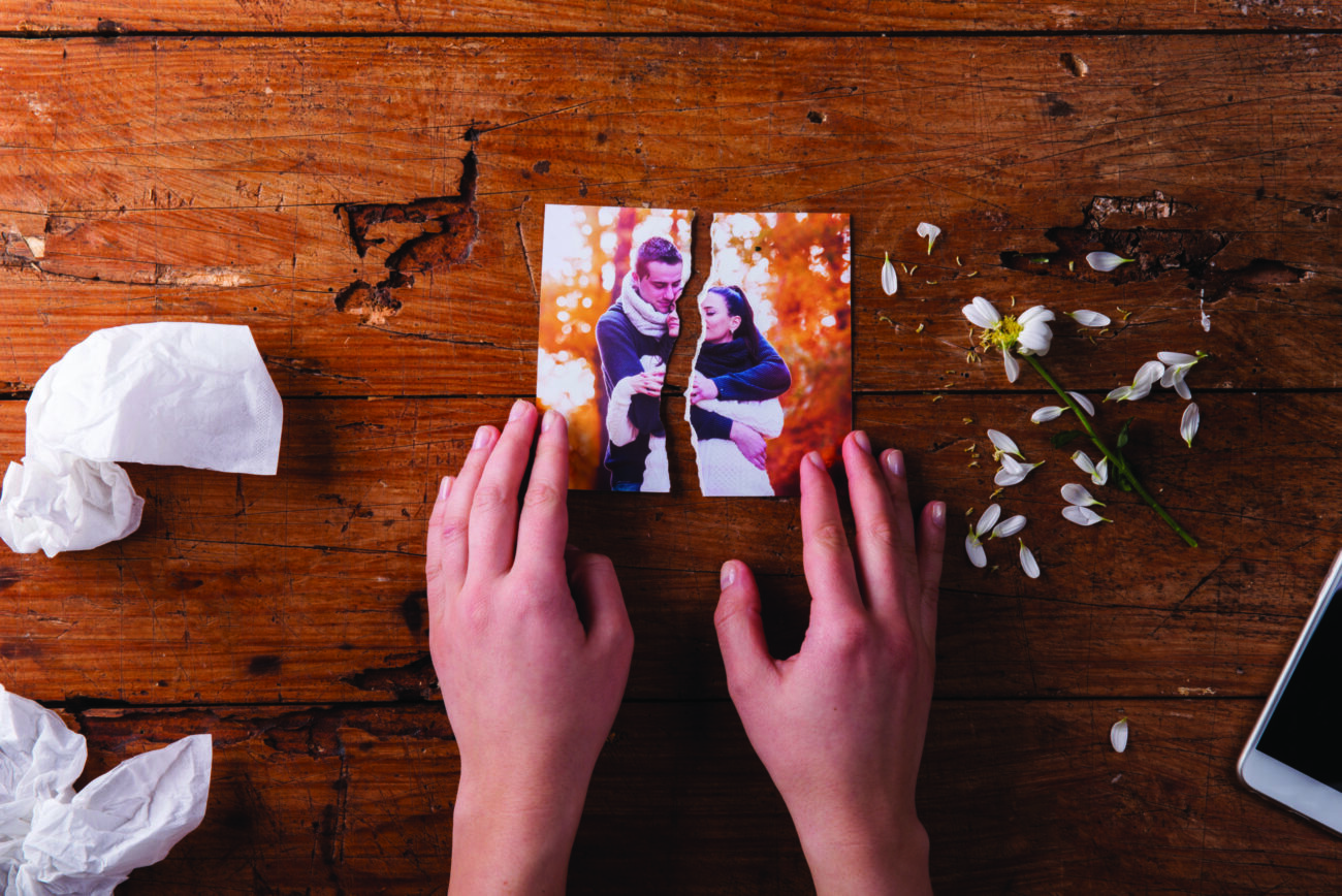 Unrecognizable sad woman holding torn picture of couple in love.