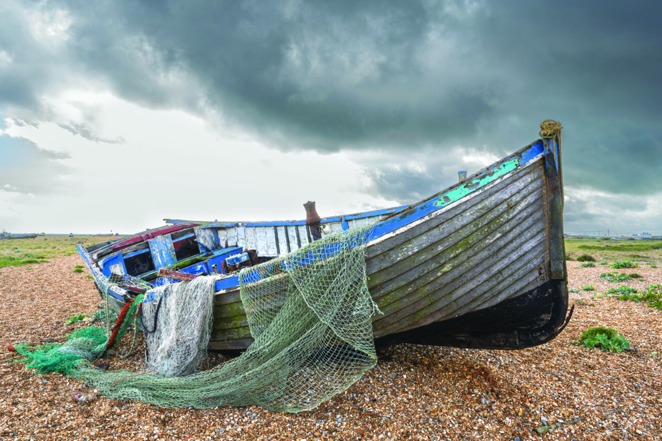 net draped over an abandoned fishing boat on the beach