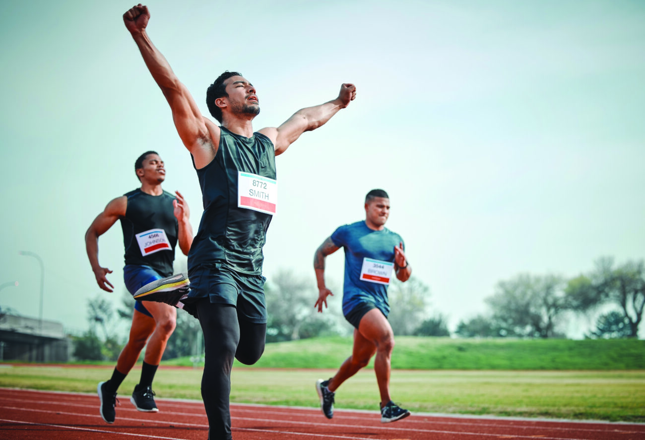 Race, winning and group of men on track for speed challenge, marathon event and celebration. Success, achievement and athlete at stadium for competition, fitness and running champion with arms up.